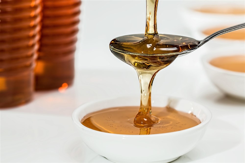 Sirup auf einem Löffel, der über eine Schale gehalten wird