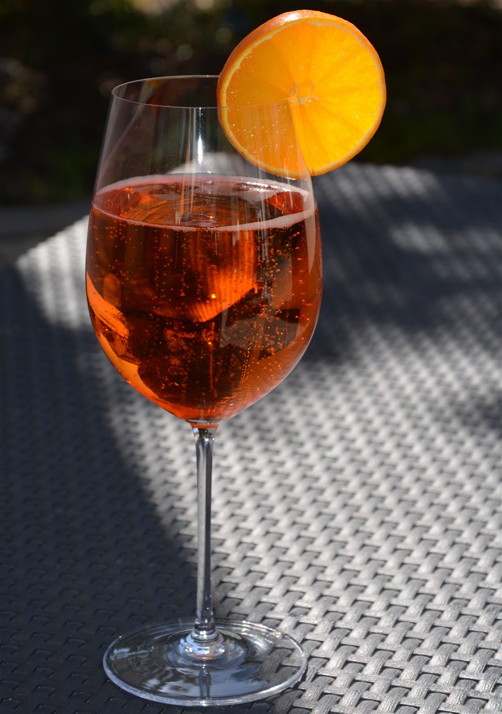 Weinglas mit Aperol-Bier-Spritz gefüllt und mit Orangenscheibe garniert