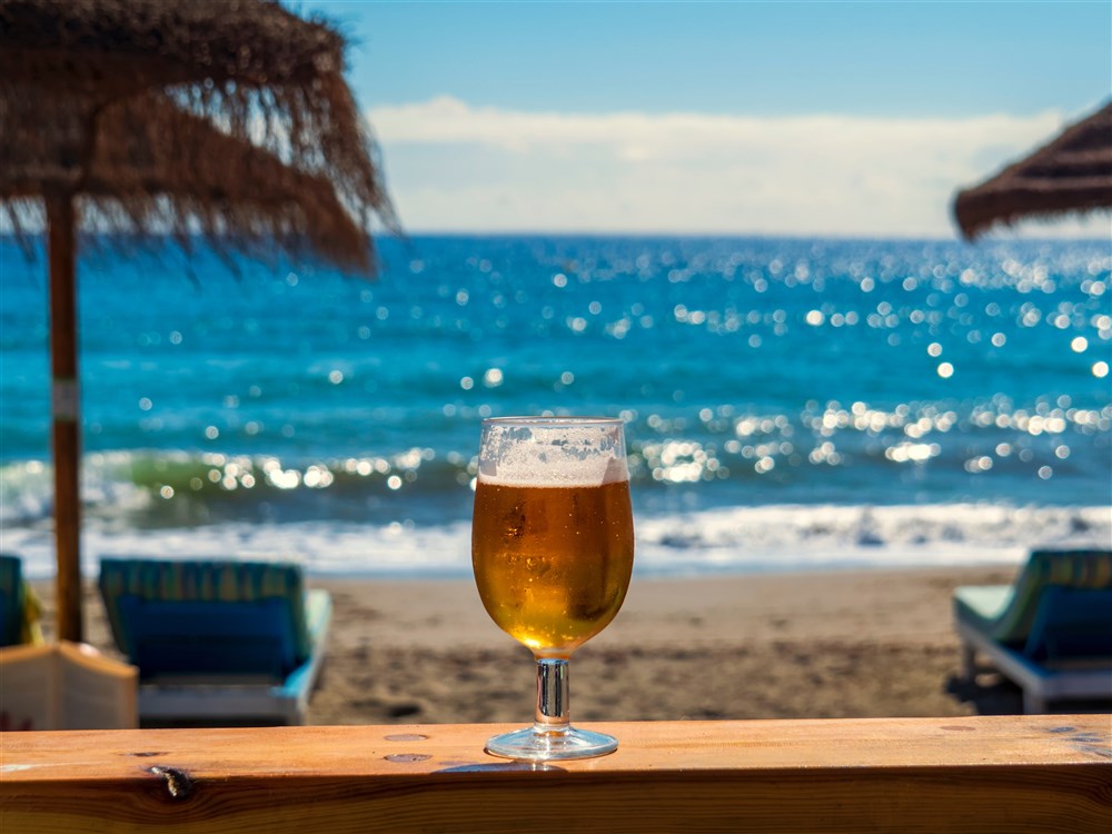 Bierglas auf Thresen stehend, im Hintergrund Strand und Meer