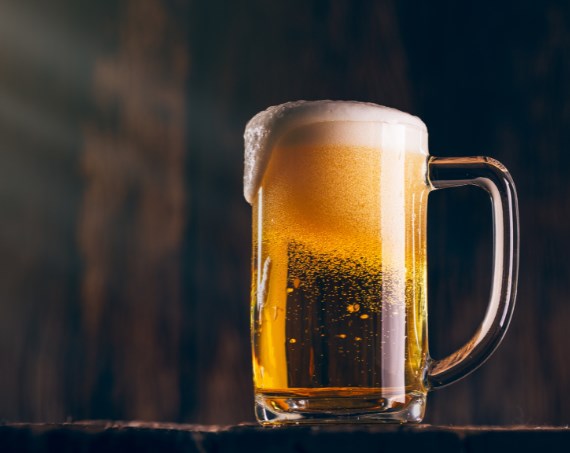 Bierkrug mit goldenem Bier und Schaum vor dunklem Hintergrund